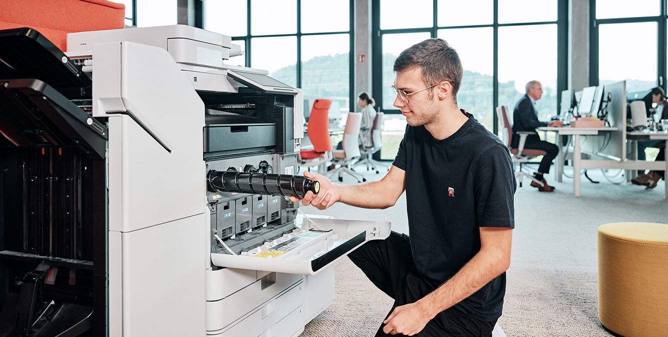 Mann kniet vor Drucksystem